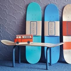 two skateboards and a toy van are next to each other in front of a wall