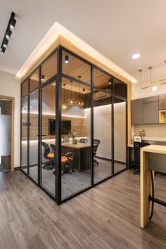 an office with glass walls and wooden flooring is seen in this image, there are two desks on the opposite side of the room