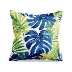 a blue and green pillow with large leaves on the front, sitting on a white background