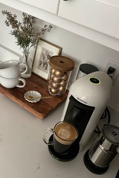 a coffee maker sitting on top of a kitchen counter next to two cups of coffee