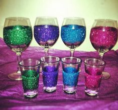 there are five glasses with different colors in them on the tablecloths and one has purple, green, blue, and pink