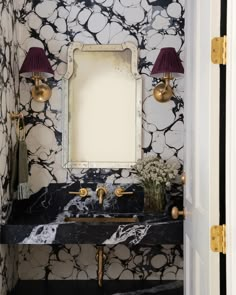 a bathroom with black and white wallpaper, gold faucets and a mirror