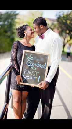 a man and woman standing next to each other holding a sign