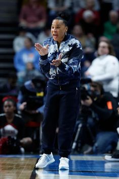 a women's basketball coach on the sidelines with her hands out in front of her