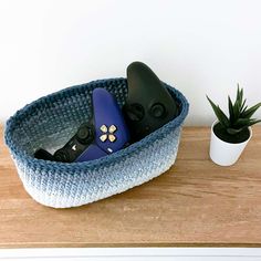 two remote controls are in a basket next to a potted succulent plant