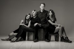 a black and white photo of four people sitting on a bench with their arms around each other