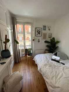 a bed room with a neatly made bed next to a window and a wooden floor