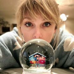 a woman is looking through a snow globe with a house in the glass ball on it