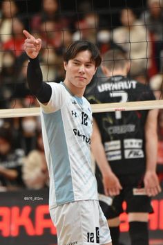 a young man standing in front of a volleyball net with his hand up to hit the ball