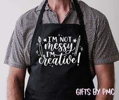 a man wearing an apron that says i'm not messy, i'm creative