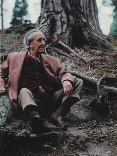 an old man sitting on the ground next to a tree