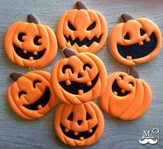 six decorated pumpkins sitting on top of a wooden table