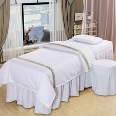 a white bed sitting in front of a window next to a pair of stools