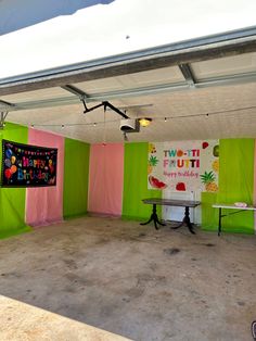 an empty room with two tables and posters on the wall behind them, in front of a green backdrop