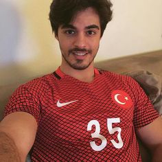 a man sitting on top of a couch wearing a red shirt with the number 35 on it