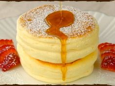 stack of pancakes with syrup and strawberries on white plate, ready to be eaten