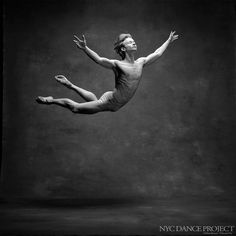 black and white photograph of a man in the air with his legs spread out as he is