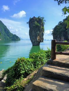 steps lead down to the water near an island in the middle of the ocean with green vegetation on both sides