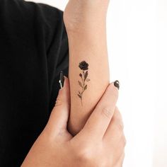 a woman's arm with a rose tattoo on her left wrist and the other hand