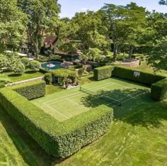 an aerial view of a tennis court in the middle of a lawn with hedges on it