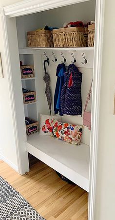 a white bench with baskets and umbrellas on it in a room next to a door