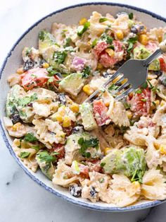 a bowl filled with pasta salad and a fork sticking out of the top one side