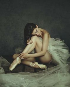 a woman sitting on the floor in ballet shoes