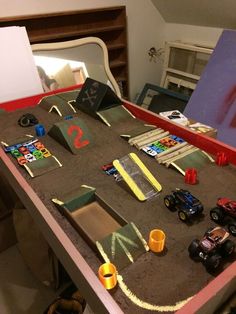 a table topped with lots of toy cars on top of carpeted floor next to a mirror