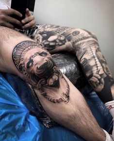 a man with tattoos on his legs is laying down and holding a cell phone in his hand