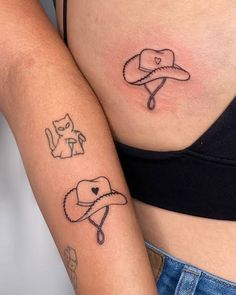 two women with tattoos on their stomachs, one has a hat and the other has a cat