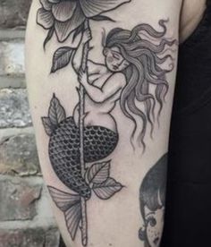 a woman with a rose on her arm and a fish in the water next to it