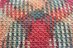 a close up view of a multicolored knitted area rug on the floor