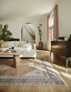 a living room filled with furniture and a stair case next to a large window on the wall