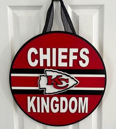 a kansas chiefs door hanger hanging on a white door with black and red stripes