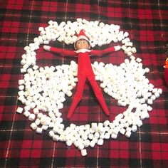 an elf is surrounded by marshmallows in the shape of a circle on a plaid tablecloth