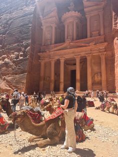 a group of people standing in front of a building with camels