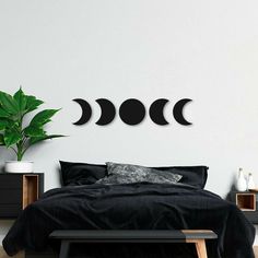 three phases of the moon on a white wall above a bed with black linens