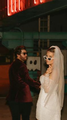 a bride and groom standing in front of a neon sign