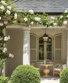 an outdoor dining area with white flowers on the arbor and potted plants around it