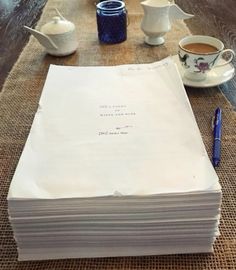 a stack of papers sitting on top of a table next to a cup of coffee