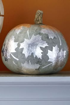 two painted pumpkins sitting on top of a white mantle next to an orange wall