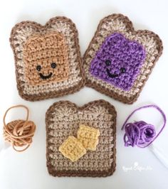 three crocheted toasters with faces on them and yarn next to each other