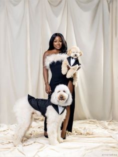 a woman in a black dress holding two dogs