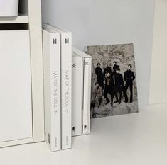 two books are sitting next to each other on a shelf in front of an album