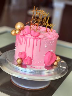 a birthday cake with pink icing and gold decorations