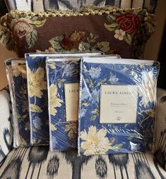 three books sitting on top of a chair in front of a floral print cover and pillow