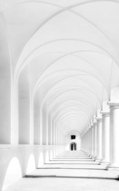 an empty white room with columns and arches