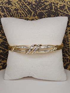 Circa 1990, a 14k yellow gold channel set baguette diamond hinged bangle bracelet. This bracelet features 62 tapered baguette diamonds totaling 0.95ctw (stamped carat weight and 14k inside). These diamonds are G/H color and VS clarity. Fit's 7.25" wrist. Condition is excellent. Weight is 18.6 grams. Thanks for looking. ERA - Circa 1990, Modern Vintage METAL / MATERIAL - 14k yellow gold MARKINGS - stamped carat weight and 14k inside CONDITION - The overall condition is very good! A true representation of 1990s-era jewelry! SIZE / MEASUREMENTS - Fit's 7.25" wrist. / Weight is 18.6 grams.  VINTAGE/ANTIQUE/HANDMADE - This item is VINTAGE. Add this timeless piece to your estate collection, to your wardrobe to jazz up any outfit, or gift it to an admirer of all things vintage and heirloom. Thank Diamond Bangle With Baguette Diamonds For Anniversary, Anniversary Baguette Diamond Bangle Bracelet, Baguette Diamond Bangle For Anniversary, Anniversary Bangle With Baguette Diamonds, Classic Bangle With Baguette Diamonds Cut, Anniversary Baguette Cut Diamond Bangle, Yellow Gold Diamond Bracelet With Baguette Diamonds For Anniversary, Formal Yellow Gold Bangle With Baguette Diamonds, Yellow Gold Baguette Cut Diamond Bracelet For Anniversary