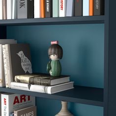 a book shelf with books and a figurine on top of it in front of a blue wall