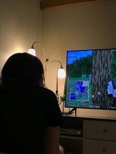 a woman sitting in front of a flat screen tv playing minecraft on the nintendo wii